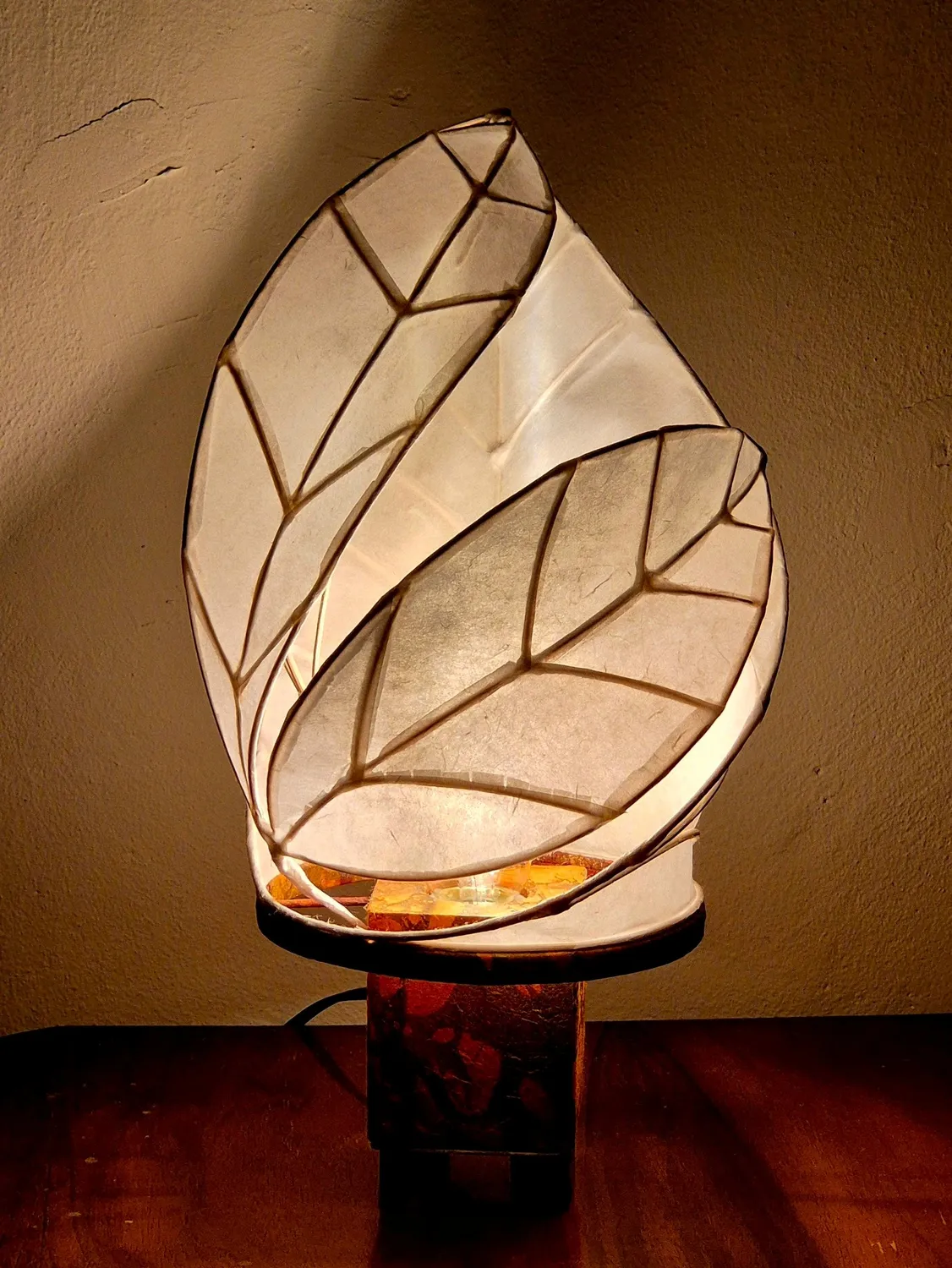 Bitte direkt hier das Foto der modernen Skulpturen-Lampe aus weißen Papierblättern mit warmem Leuchtmittel einfügen.